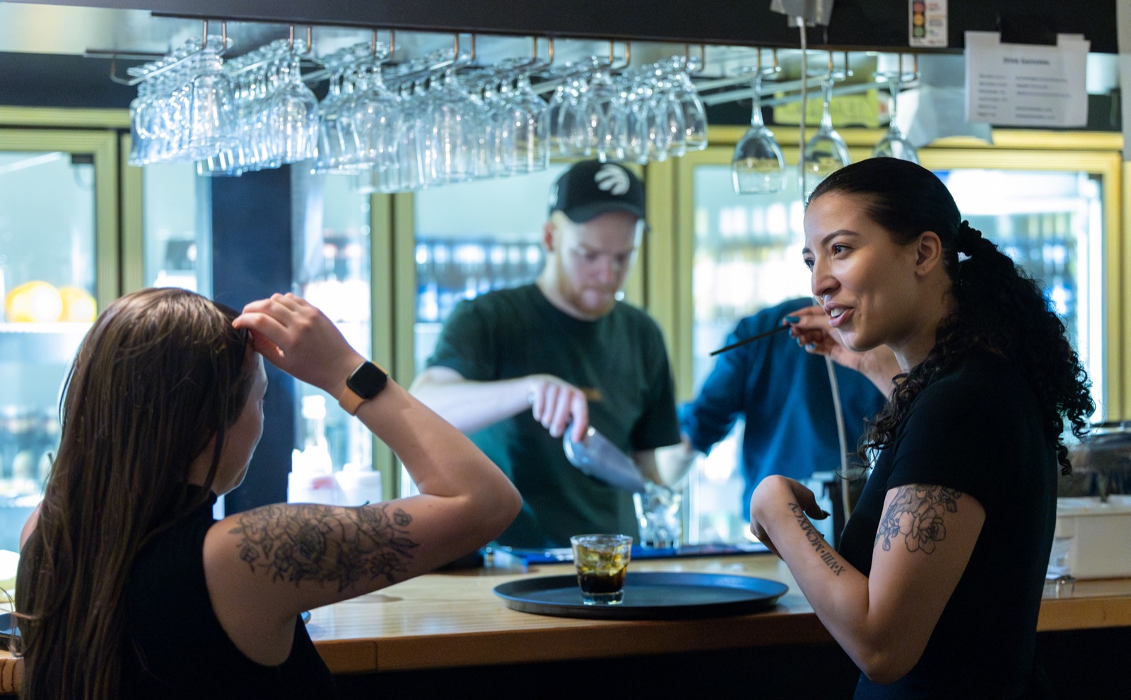 Staff at the House of Comedy Vancouver bar, a bartender shaking a cocktail while a drink waits on a tray